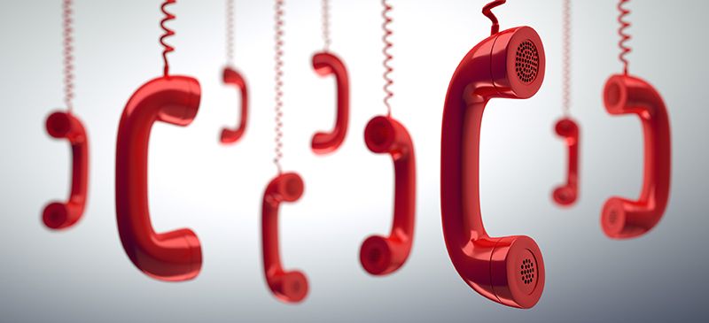 A group of vintage red telephone receivers hanging by isolated cables