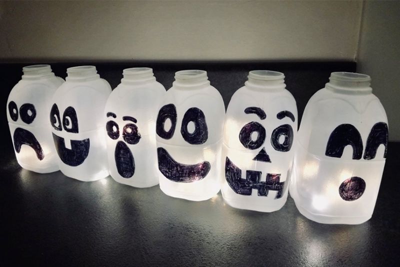 A set of DIY halloween lanterns made from plastic milk cartons with spooky faces drawn on