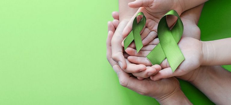 Hands holding a green ribbon for World Mental Health Day