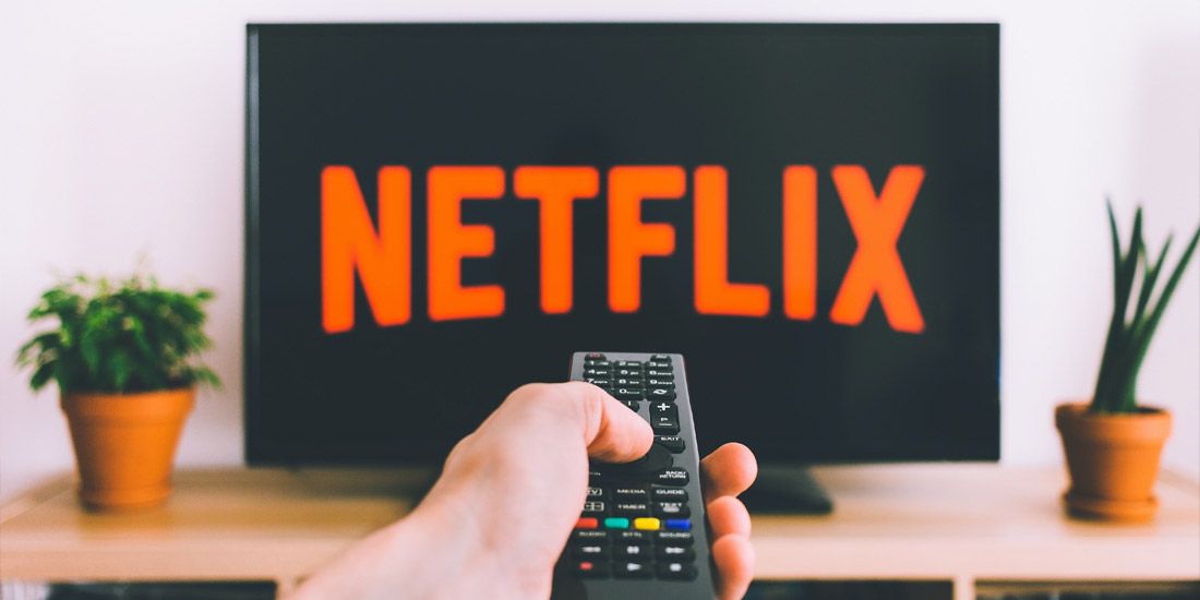 Remote control pointed at TV streaming Netflix