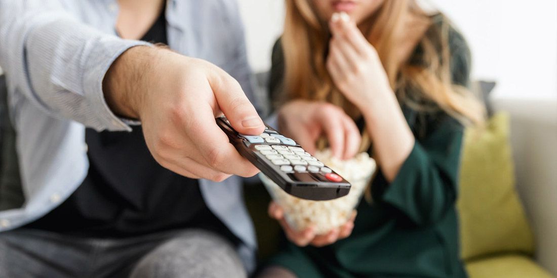 A couple sat on a sofa watching a movie