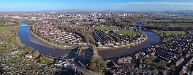 An aerial view of a river and houses on the outskirts of Preston